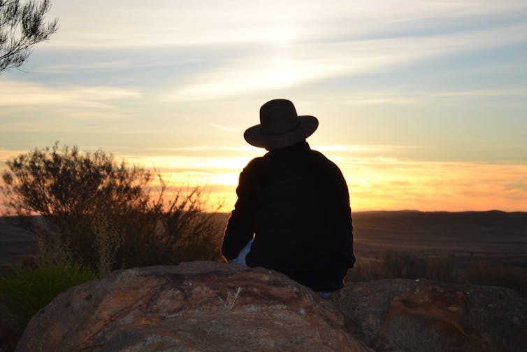 farmer sits on rock