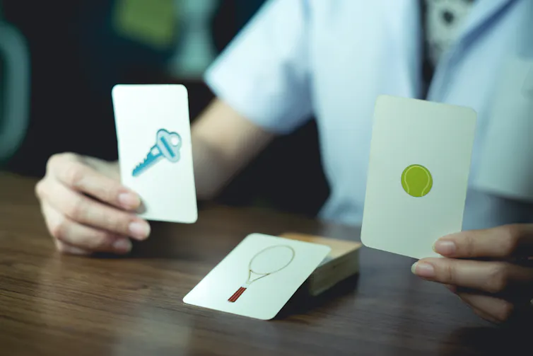 Un professionnel de la santé présente des cartes avec des images d’objets à un patient