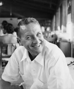 A clean-cut man in a white shirt smiles at the camera