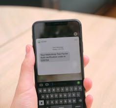 A hand holds a smartphone showing a text message on the screen