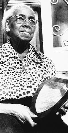 An elderly woman holds an award