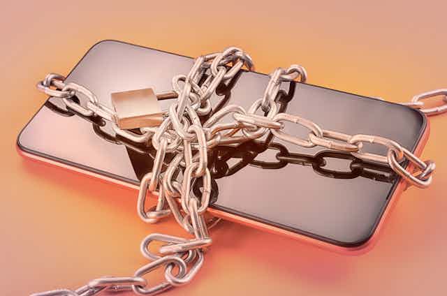 A cellphone bound in a chain with a lock.