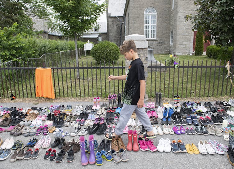 A boy puts down tobacco amid children's shoes.