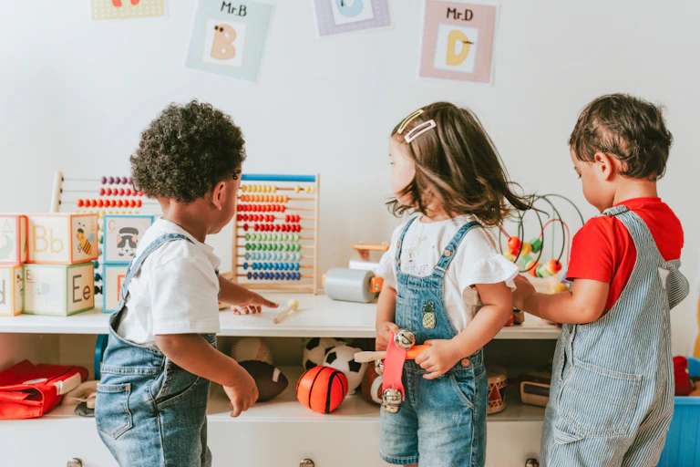 Three kids together in childcare, one pointing at an abacus.