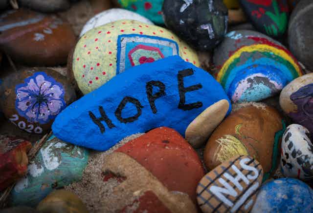 Rocks painted with rainbows, flowers and the word HOPE