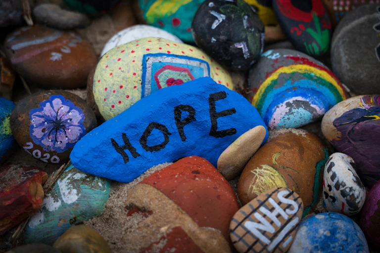 Rocks painted with rainbows, flowers and the word HOPE