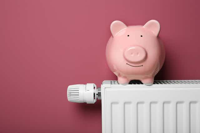 A piggy bank sits on a white radiator.