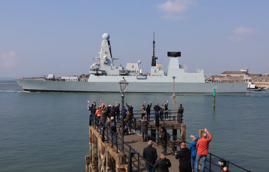 Members of public wave as the British destroyer HMS Defender leaves Portsmouth Harbour, May 2021