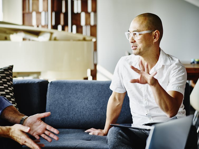 A man motioning with his hands as he explains something to another person.