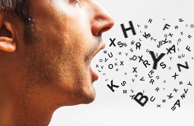 A close up, profile-view photo of a man with an assortment of letters appearing to come out of his mouth