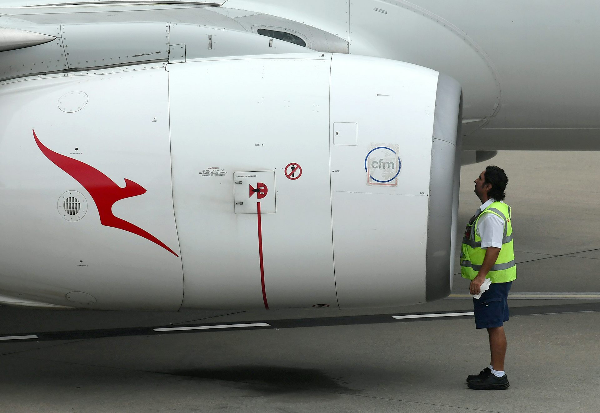 Qantas employee inspects jet engine
