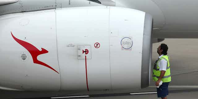Qantas employee inspects jet engine