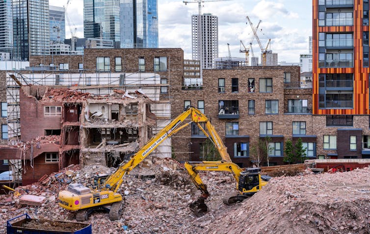 A digger on an urban construction site featuring new homes and high-rise buildings