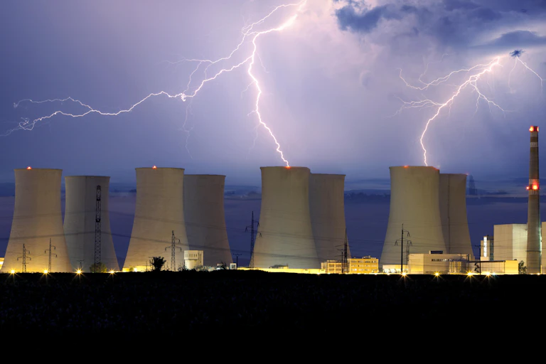 Cooling towers of a nuclear power plant with lightning in the background.