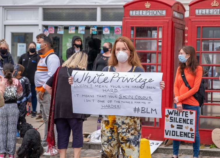 A protester holding up a sign that says 'white privilege doesn't mean your life hasn't been hard, it means your skin colour isn't one of the things making it harder'