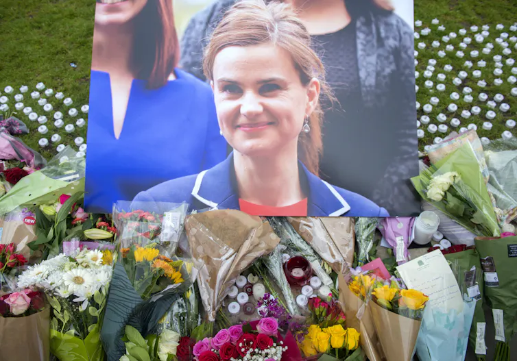 A photograph of murdered MP for Batley and SPen, Jo Cox, above bouquets of flowers.