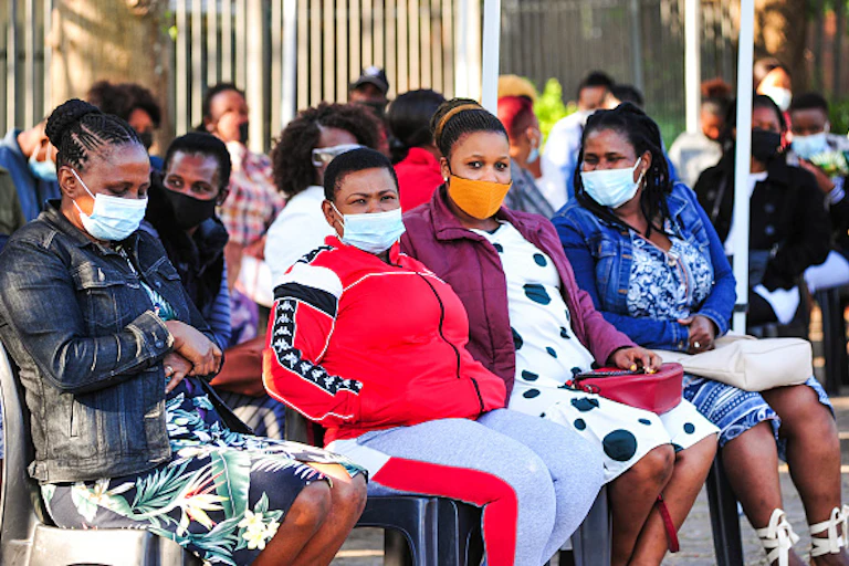 Women wearing face masks sit on chairs in rows