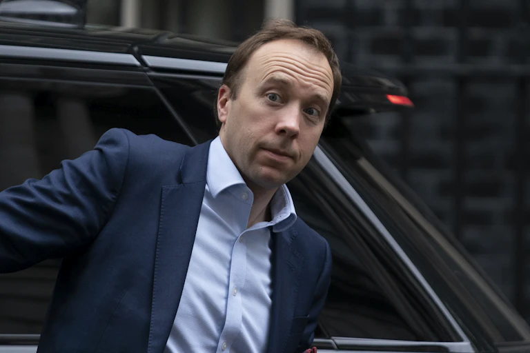 Health secretary Matt Hancock looking surprised as he exits a car