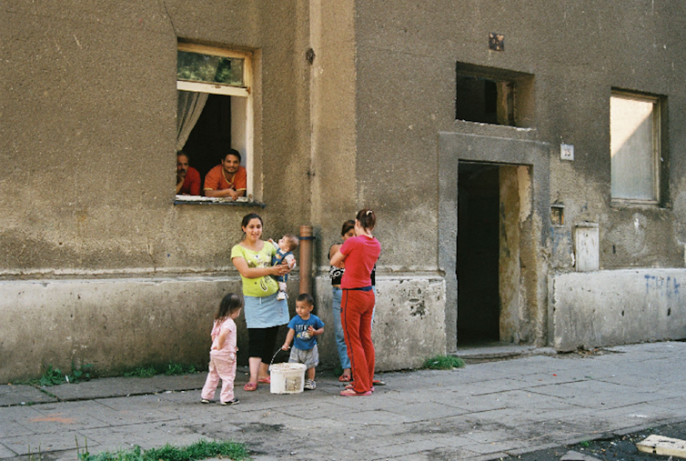 A Roma family outside a slum building.