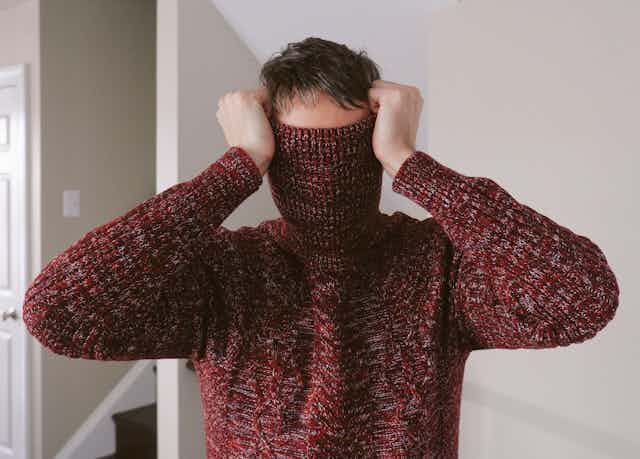 man with turtleneck of sweater pulled over his face