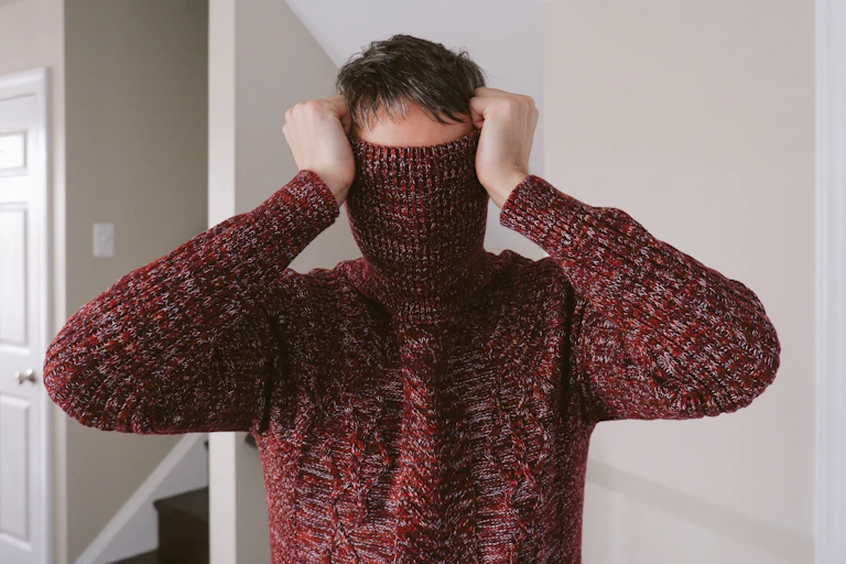 man with turtleneck of sweater pulled over his face