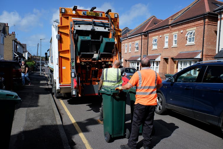 Two men load bins onto a lorry
