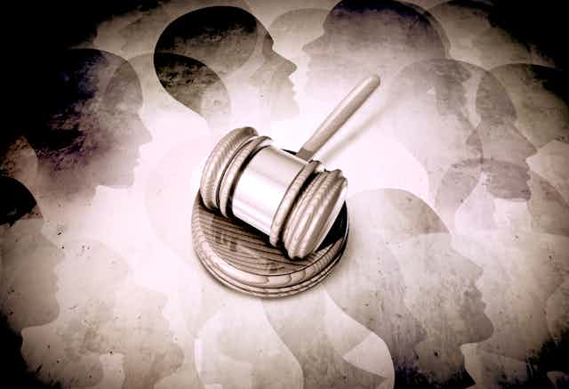 Sepia-toned gavel against a background of abstract human faces