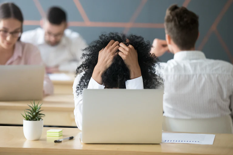 Woman with head in hands over laptop.