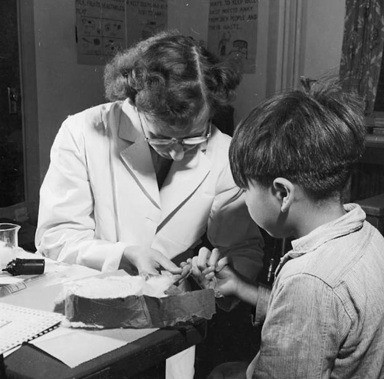 Black and white photo: a nurse takes a blood sample from a little boy