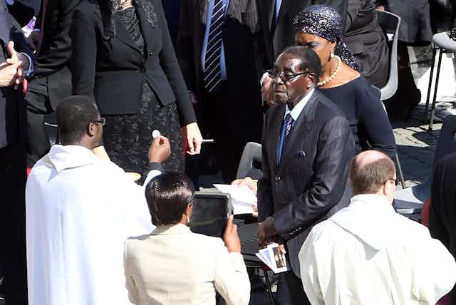 Zimbabwe's ruler Robert Mugabe flanked by his wife Grace receives the communion during the holy mass  held by Pope Francis at St. Peter's Square on October 19, 2014 in Vatican City, Vatican