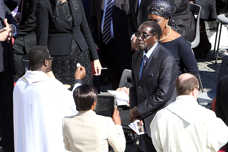 Zimbabwe's ruler Robert Mugabe flanked by his wife Grace receives the communion during the holy mass held by Pope Francis at St. Peter's Square on October 19, 2014 in Vatican City, Vatican