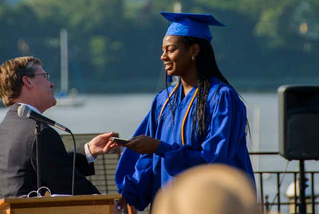 A Black female high schooler receives her diploma.