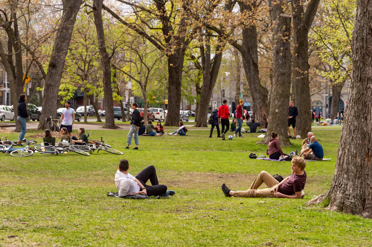 Des gens sont couchés dans l’herbe, dans un parc