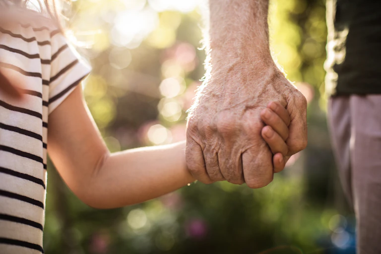 An old man, holding the hand of a young girl