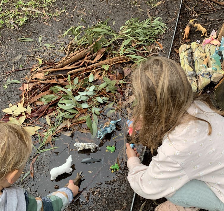 Kids playing with little figurines in the mud.