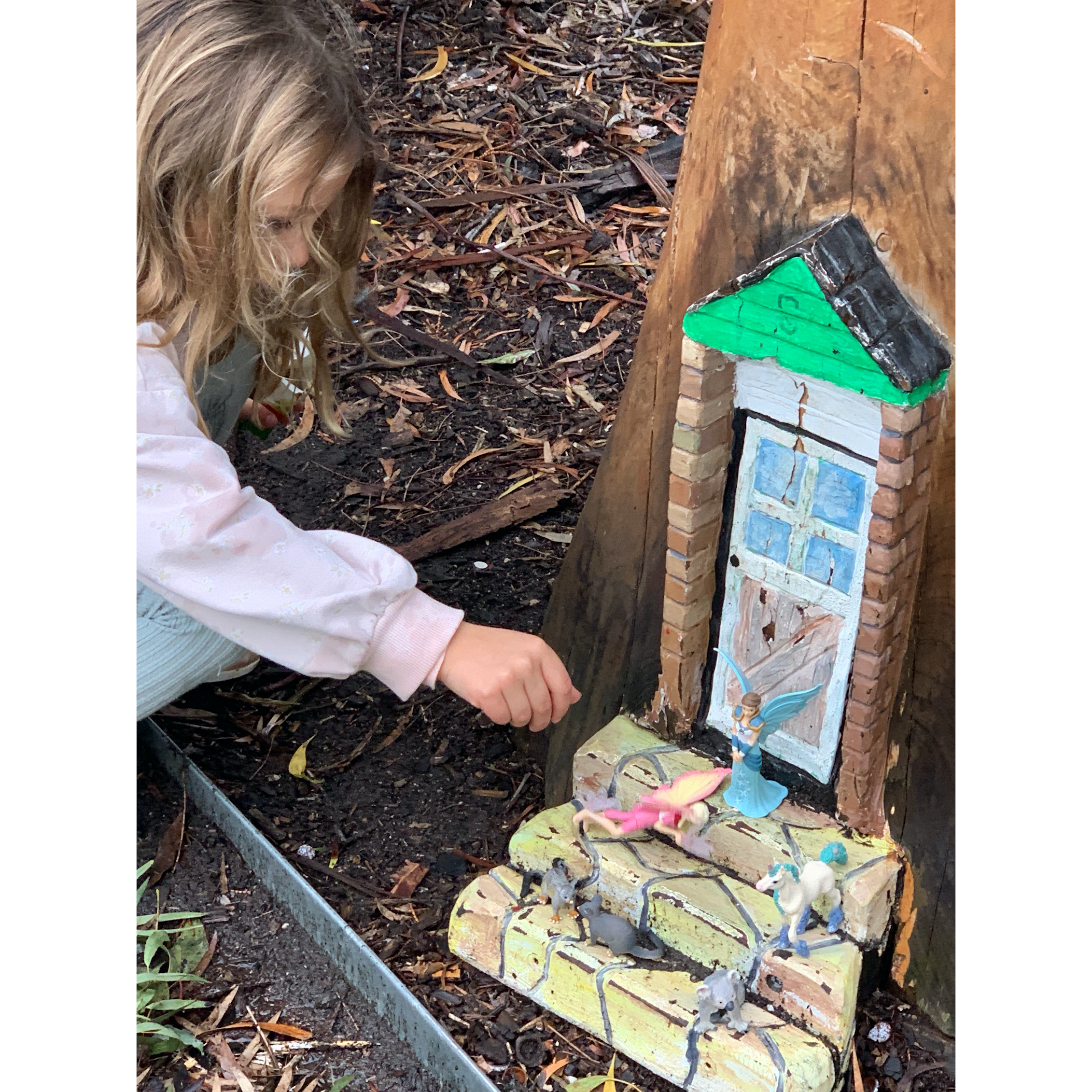 Girl playing with a fairy door in a tree.