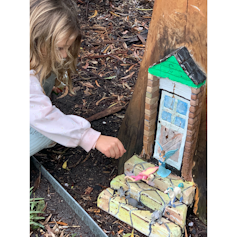 Girl playing with a fairy door in a tree.