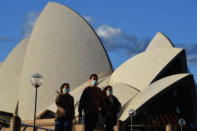 People wearing masks in front of the Sydney Opera House