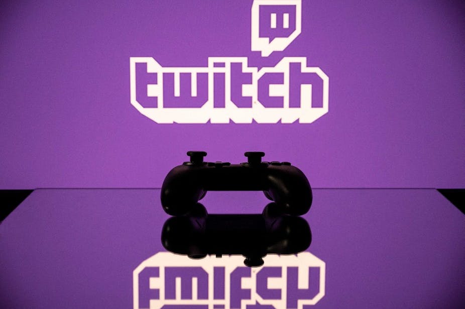 Une manette de jeu devant le logo violet du site de streaming Twitch