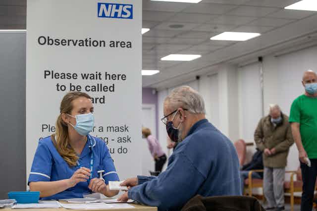 A nurse speaking to a man at an NHS vaccination centre