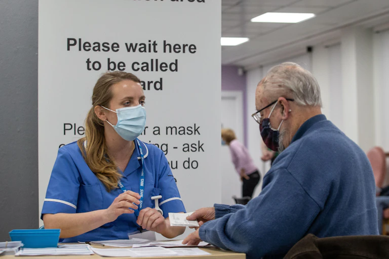 A nurse speaking to a man at an NHS vaccination centre