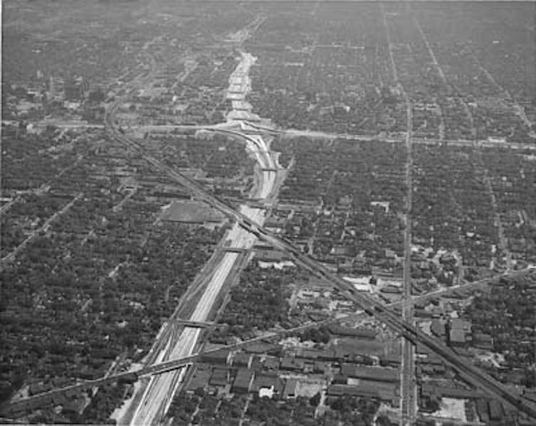 A historic view of Detroit, Michigan, showing the city bisected by an interstate highway.