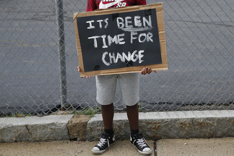Child holds painted sign that says 'It's been time for change'