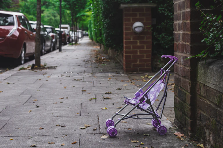 A purple stroller without a child on a sidewalk.