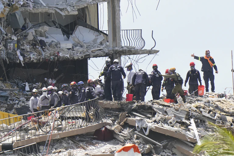 Rescue workers standing on rubble.
