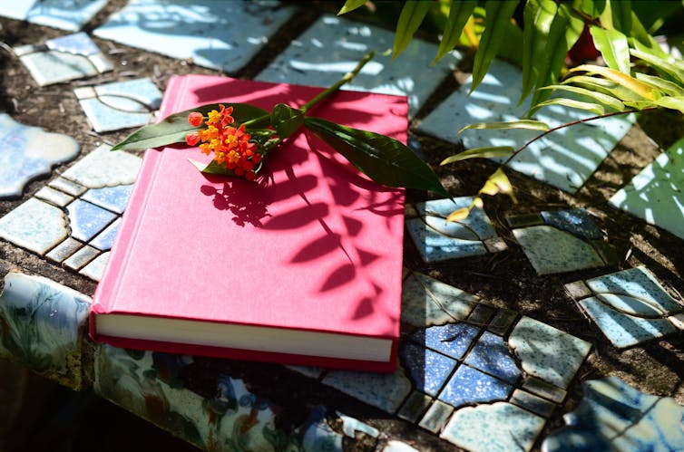 A journal sitting on tile with a flower on top.