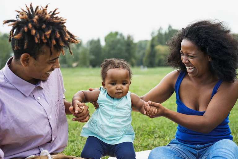 Two woman holding up kid in the park.