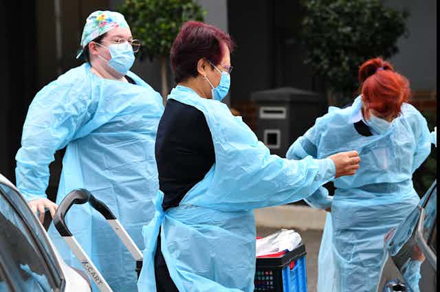 Aged-care workers put on PPE.