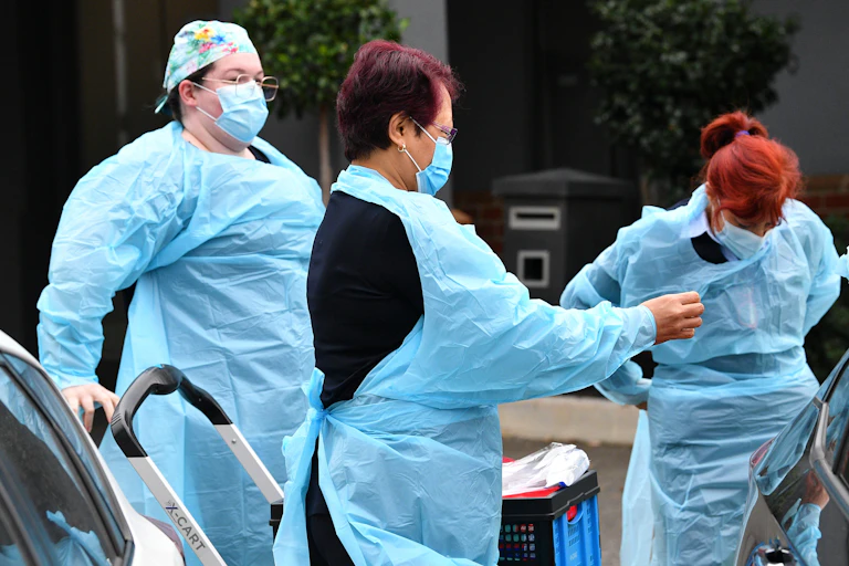 Aged-care workers put on PPE.