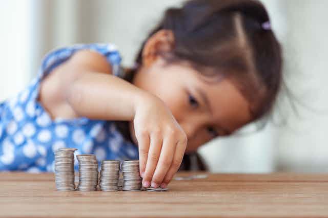 Child stacking coins in different-sized columns